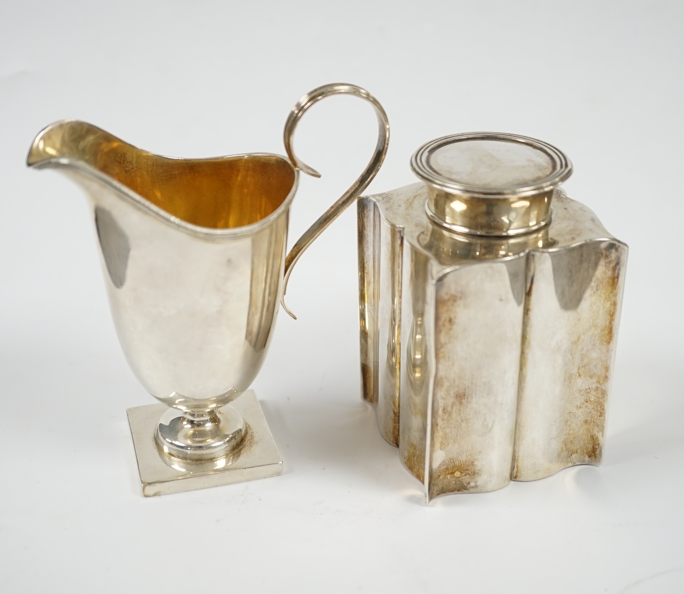 An Edwardian silver ‘bats wing’ tea caddy, Birmingham, 1906, 95mm and a George V silver cream jug. Condition - fair